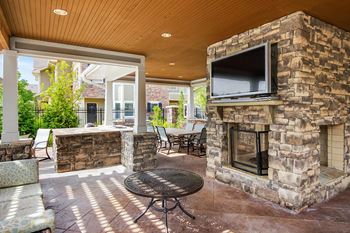 The outdoor living area has a stone fireplace and a television